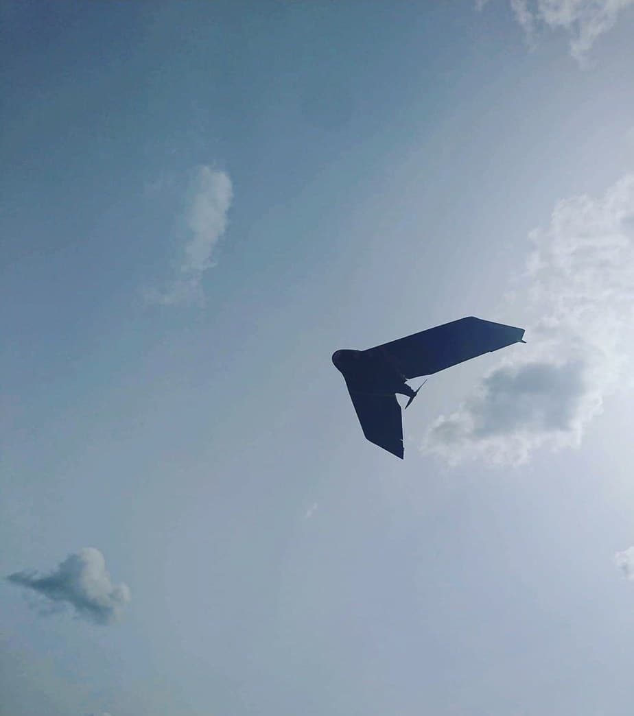 Fixed-wing mapping drone silhouetted against the sky