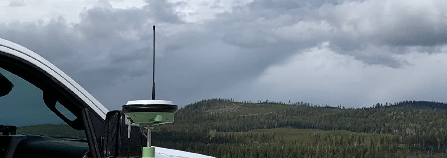 GNSS base setup on a mine haul road with cutblock hills behind