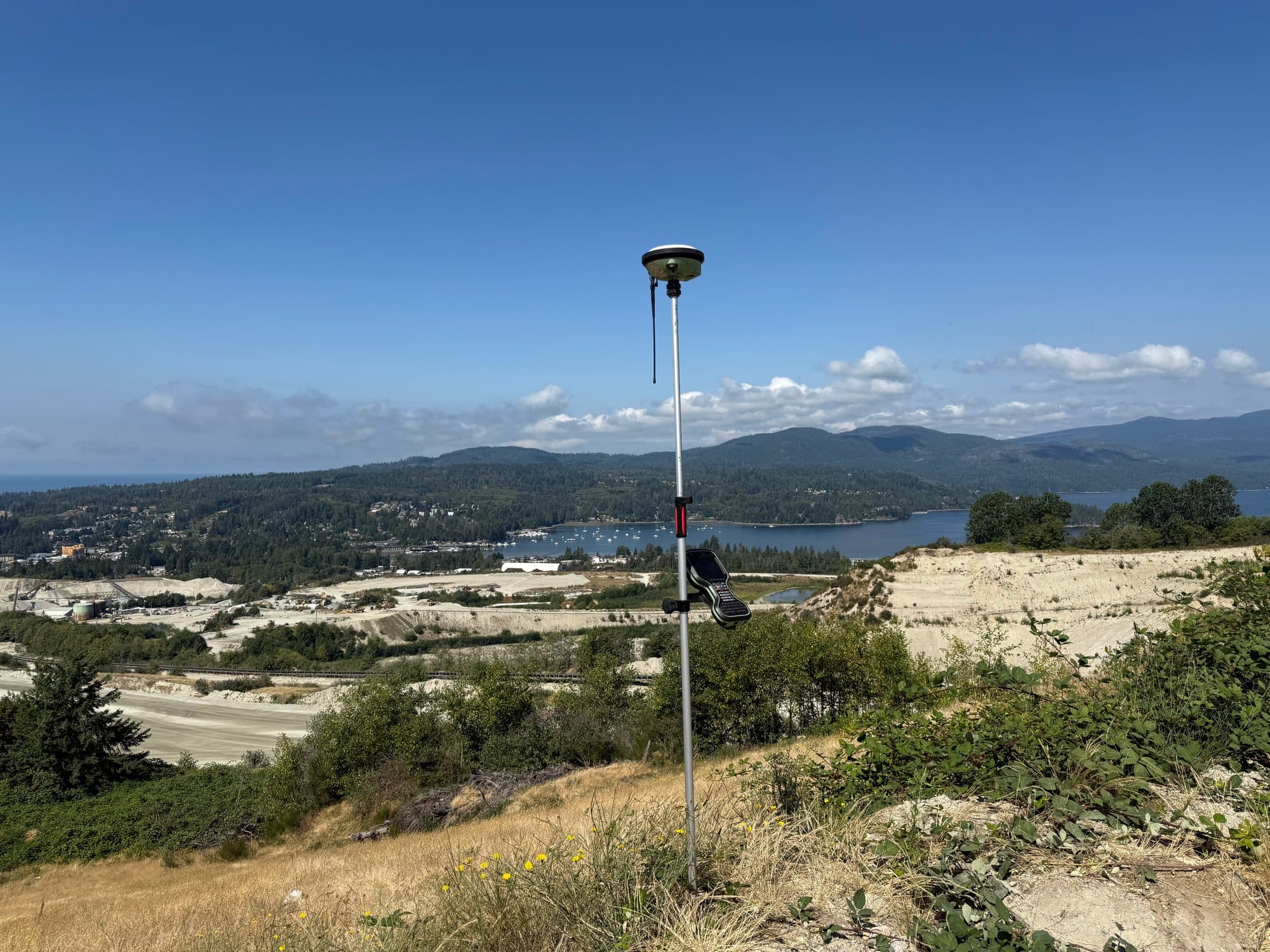 GNSS rover on a hilltop overlooking a town and lake