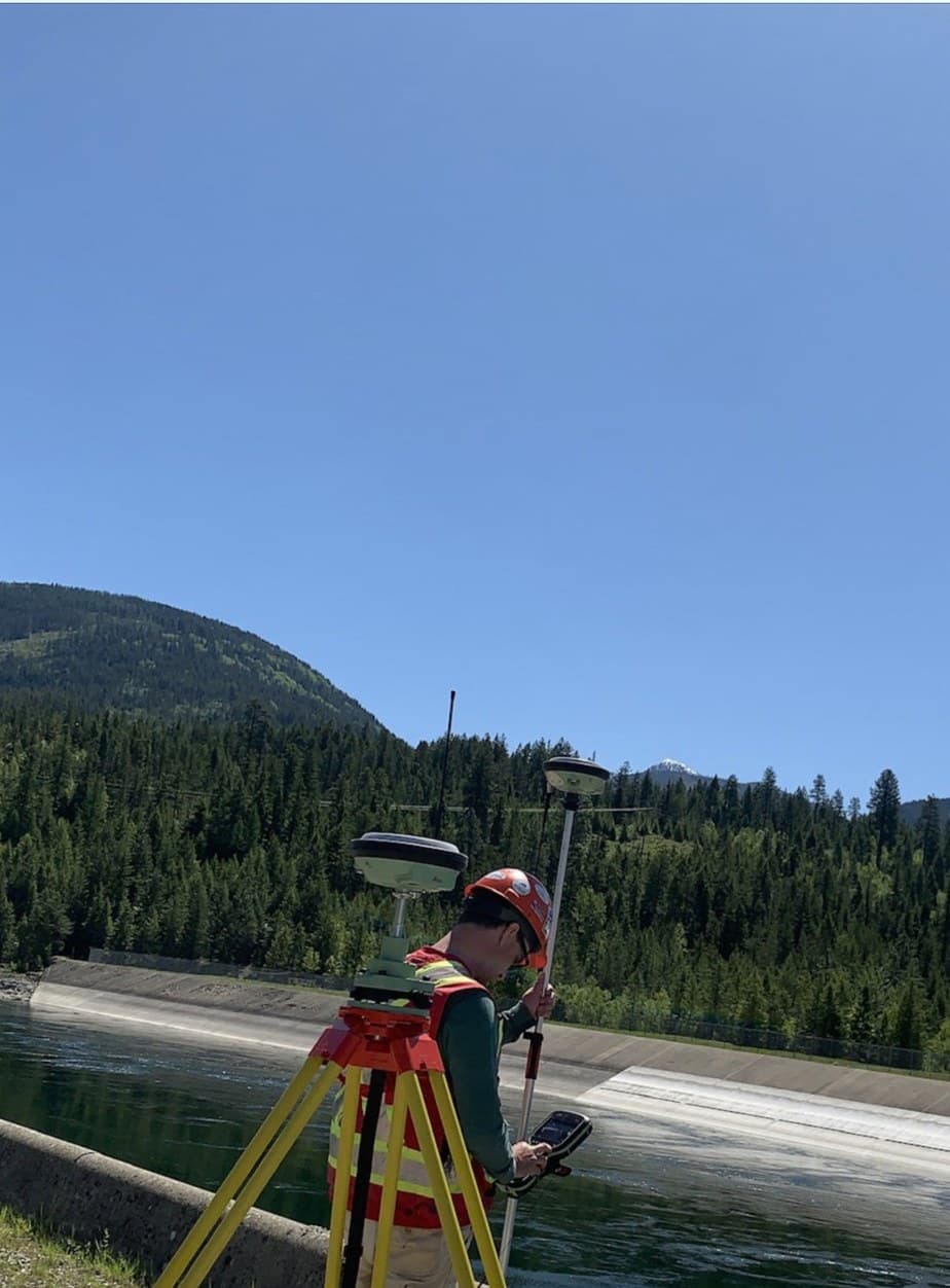 Surveyor with GNSS gear above a dam spillway