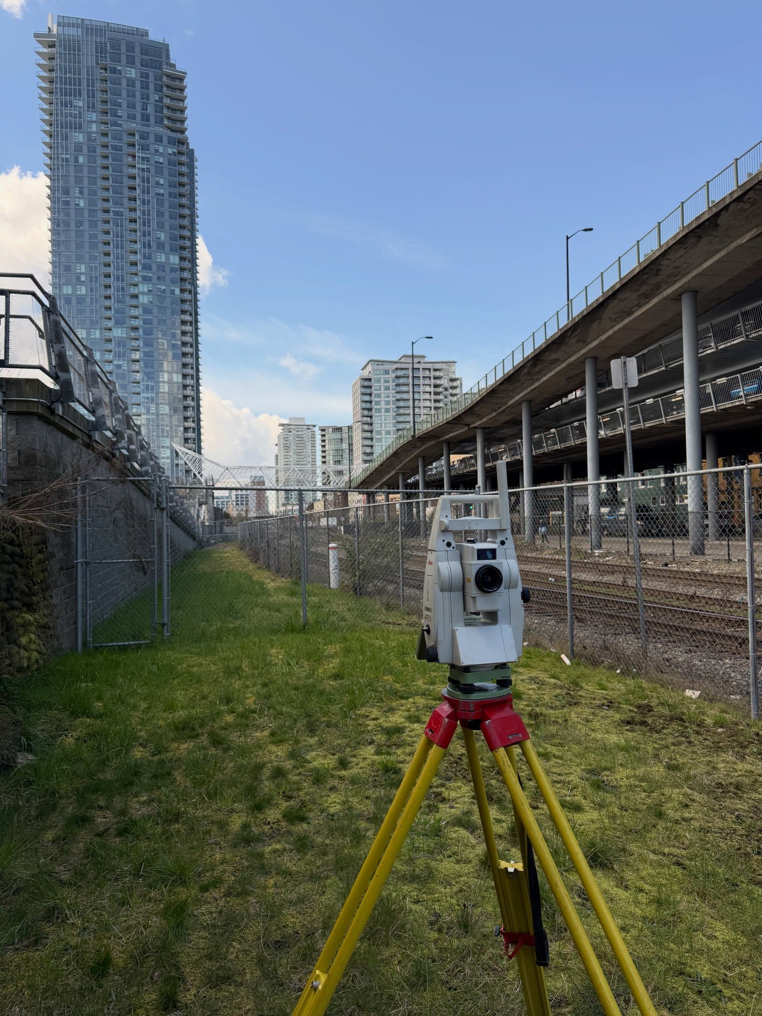 Survey along a fenced rail corridor beneath the towers