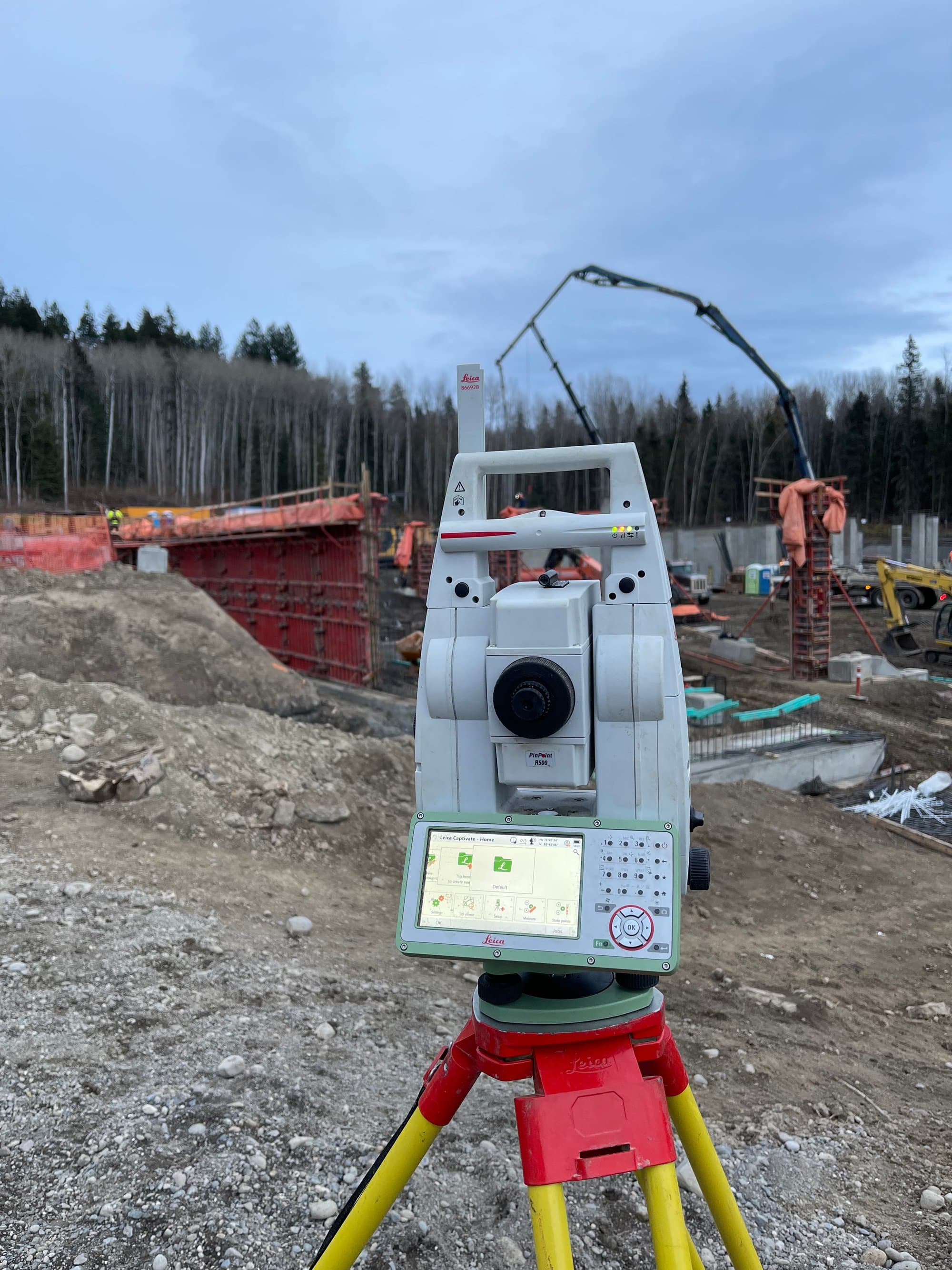 Robotic total station at formwork under a working crane