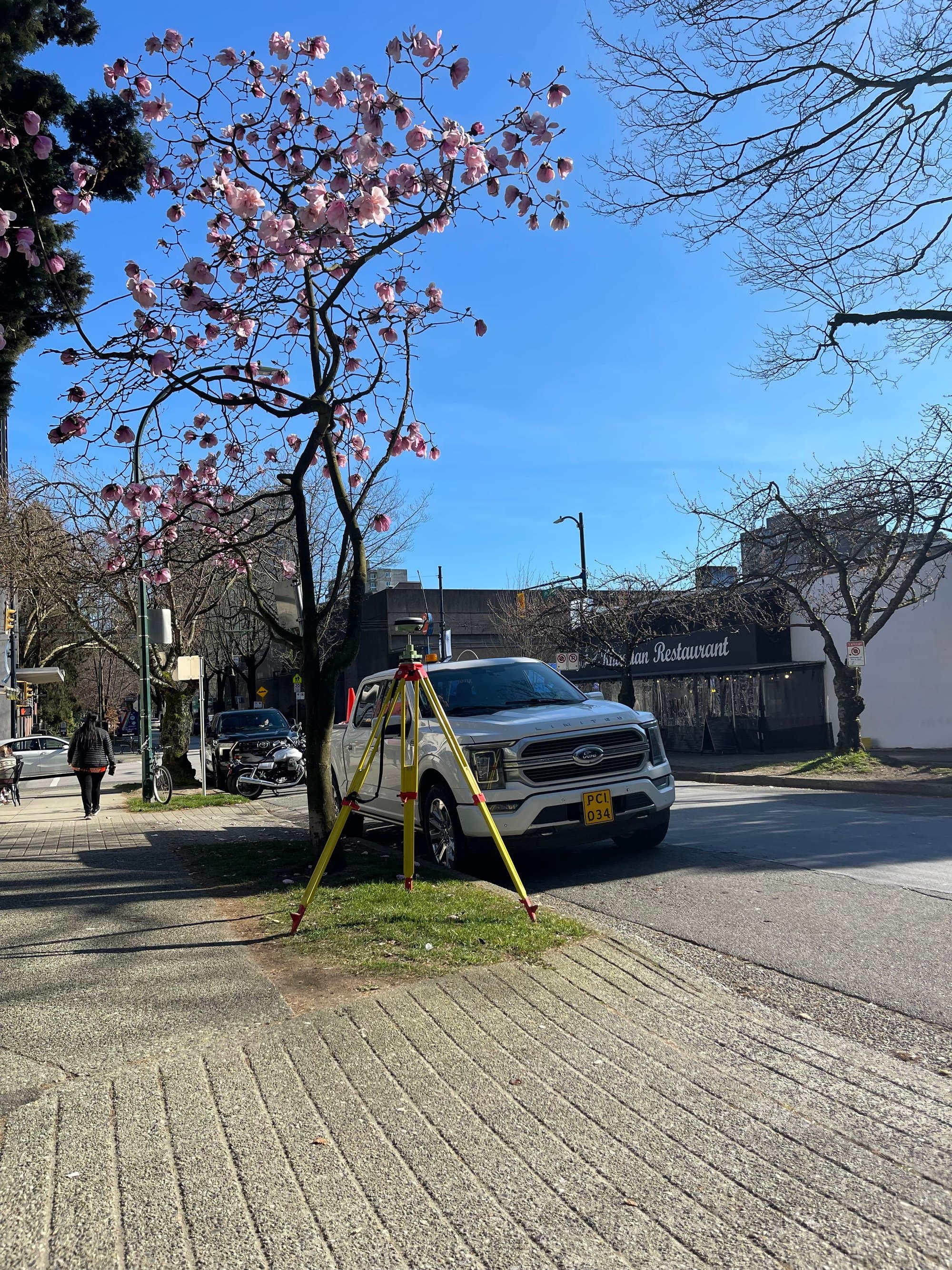 Robotic total station on a city street beside the survey truck