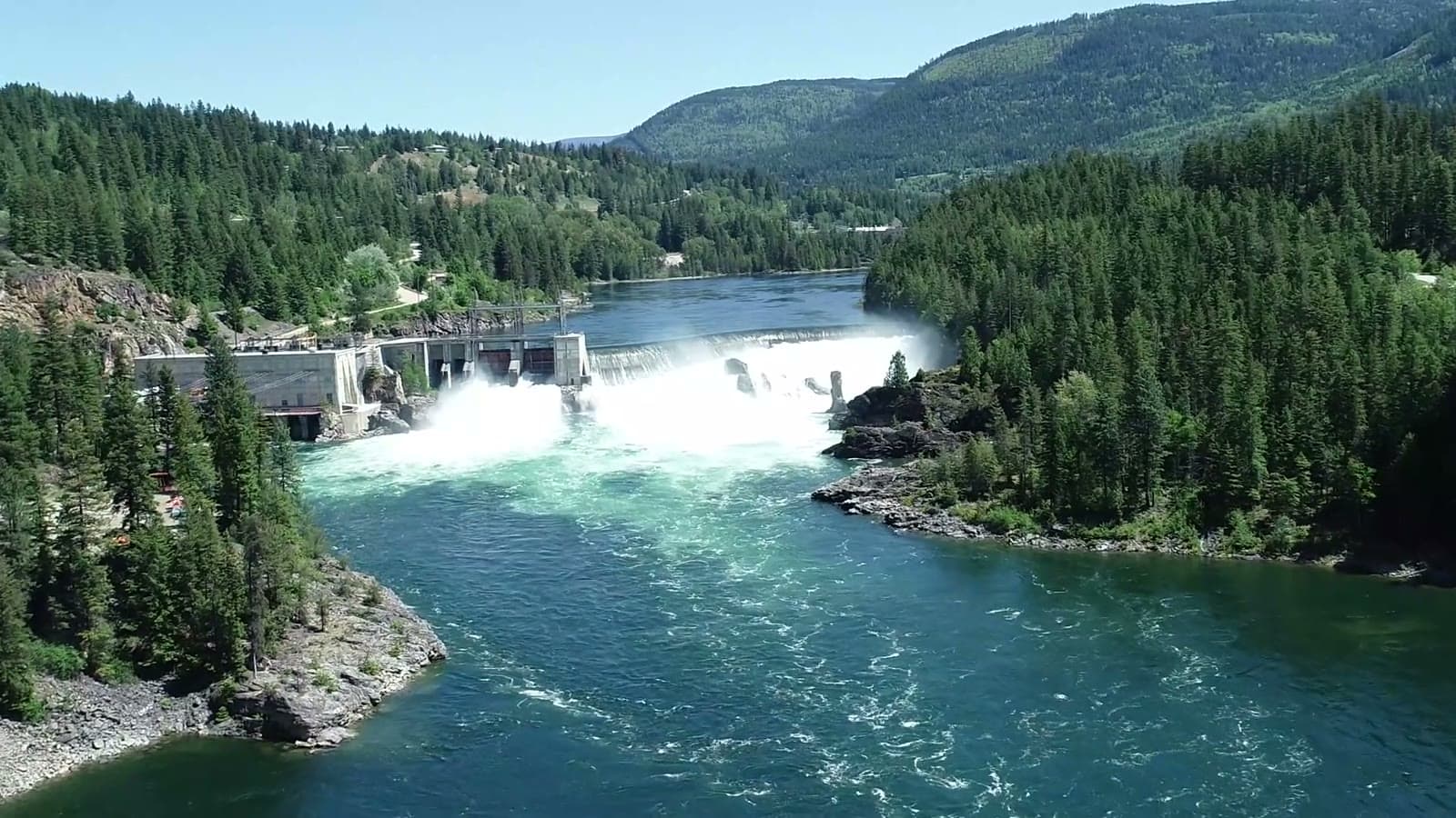 Aerial view of a hydro dam and spillway on a forested BC river