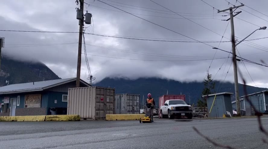 PCI technician pushing a GPR cart across a coastal townsite lot