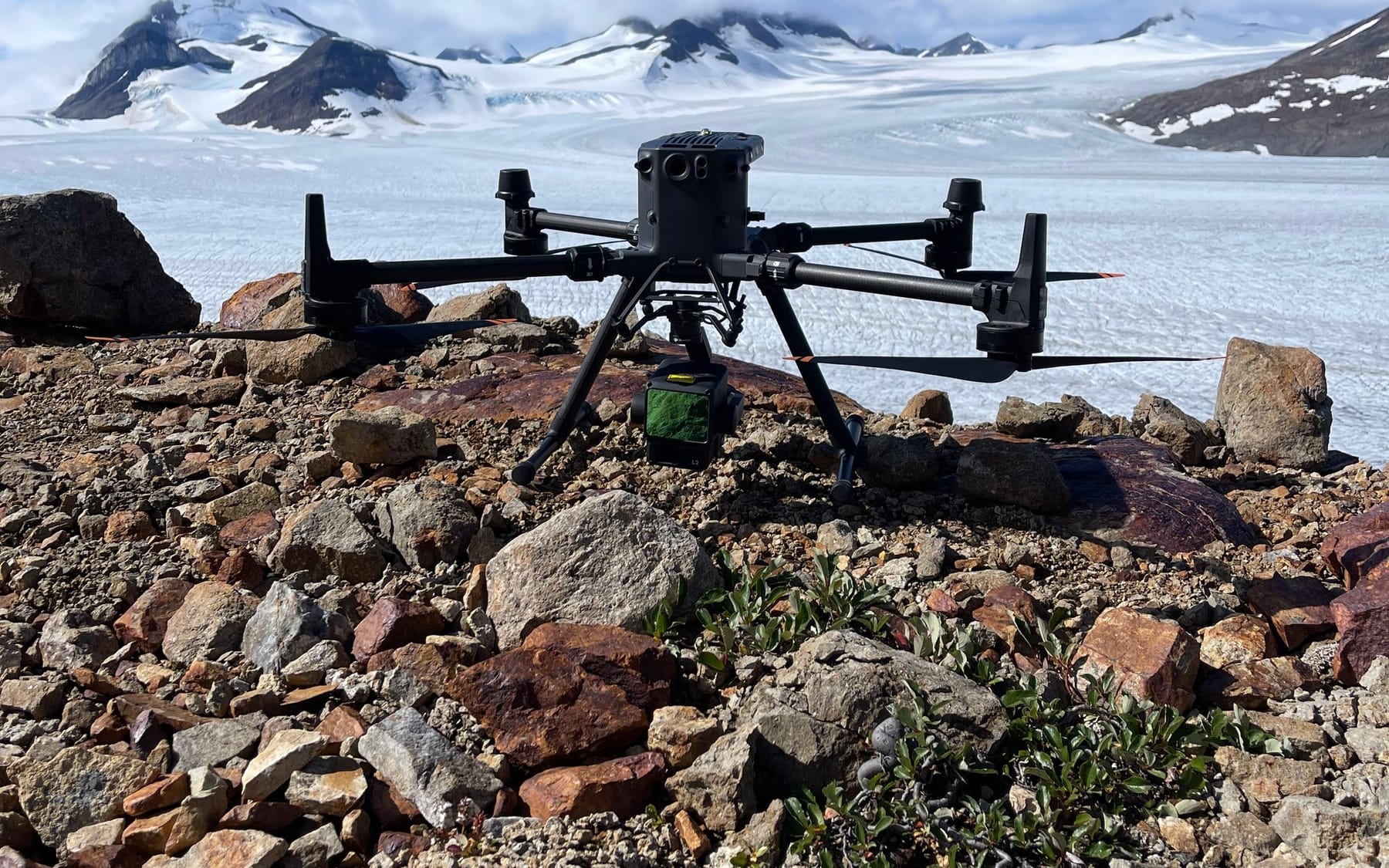 LiDAR-equipped drone staged on a rocky ridge in front of a glacier before a mapping flight