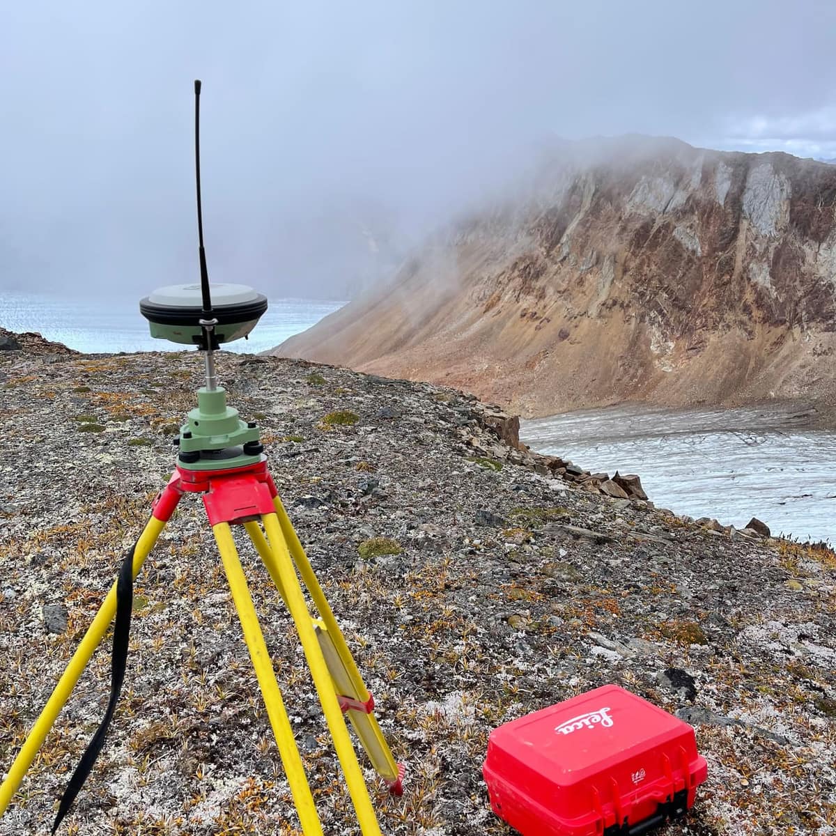 GNSS base station on a tripod at a fog-bound alpine mine site