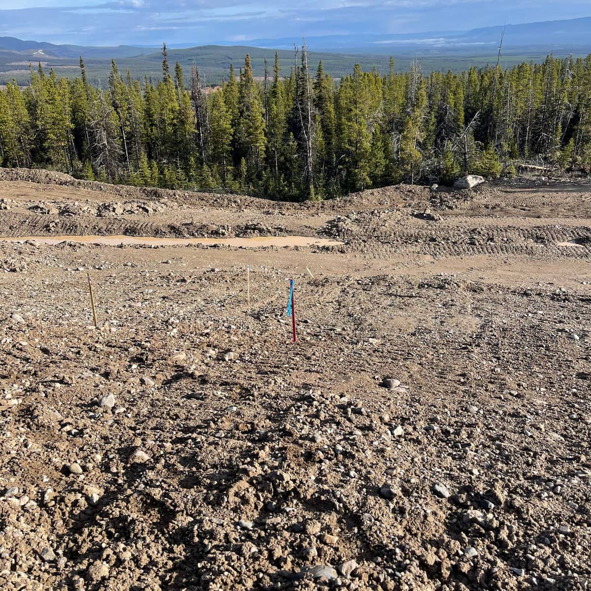 Grade stakes set on a gravel pad at a mine earthworks site