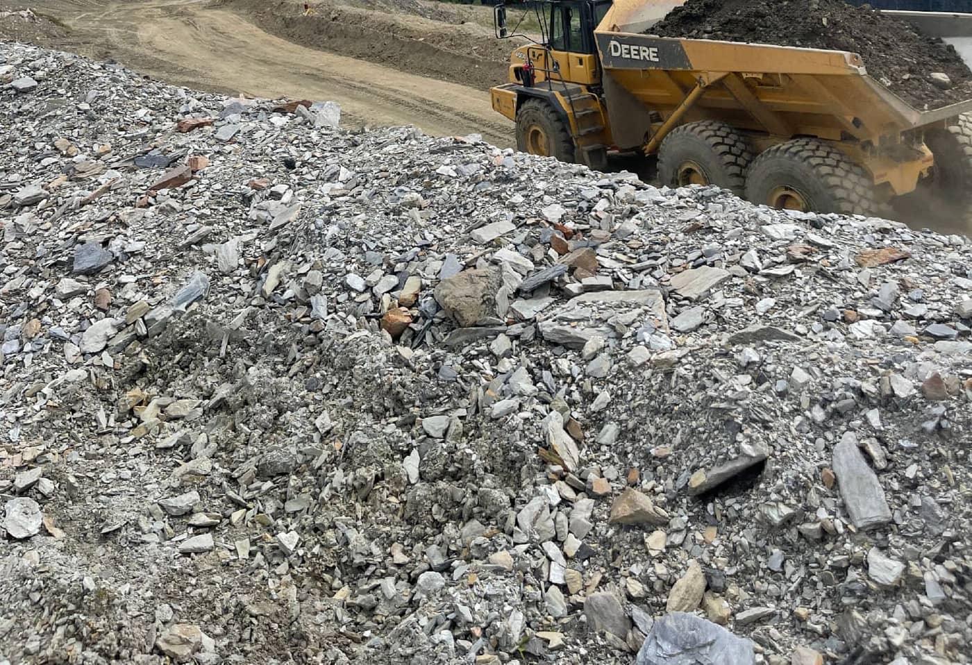 Articulated haul truck passing a waste rock pile at a northern mine