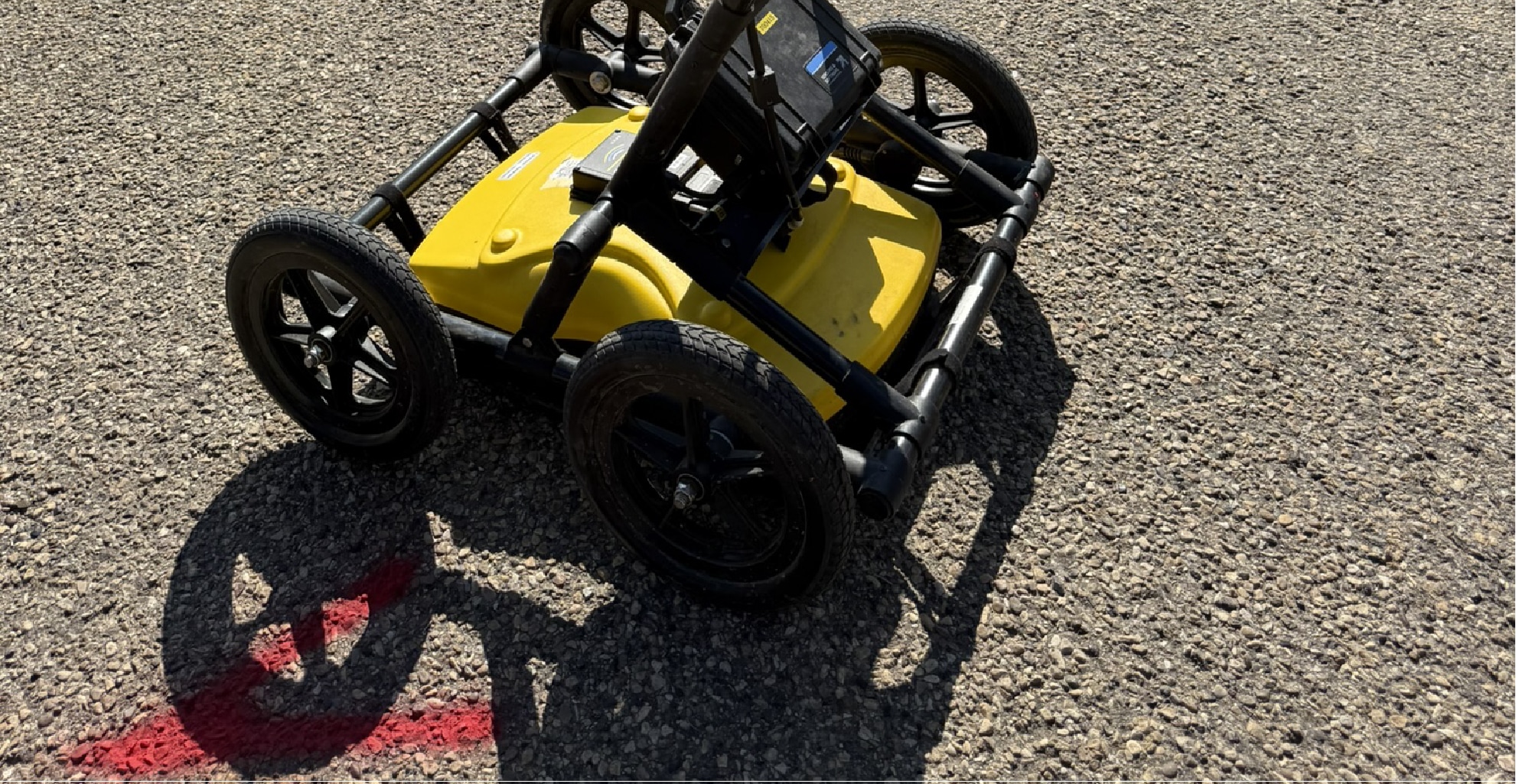 LMX200 wheeled ground penetrating radar (GPR) scanner on asphalt surface with red marking for subsurface surveying by PCI Surveys.